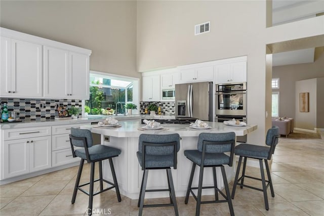 24661 Las Patranas, Yorba Linda, CA 92887 - kitchen featuring visible vents, a high ceiling, white cabinetry, tasteful backsplash, and stainless steel appliances
