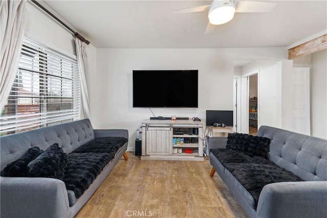 living room with ceiling fan, baseboards, and light wood finished floors