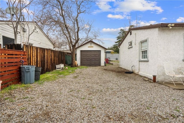 view of side of property with driveway, a detached garage, fence, an outdoor structure, and stucco siding