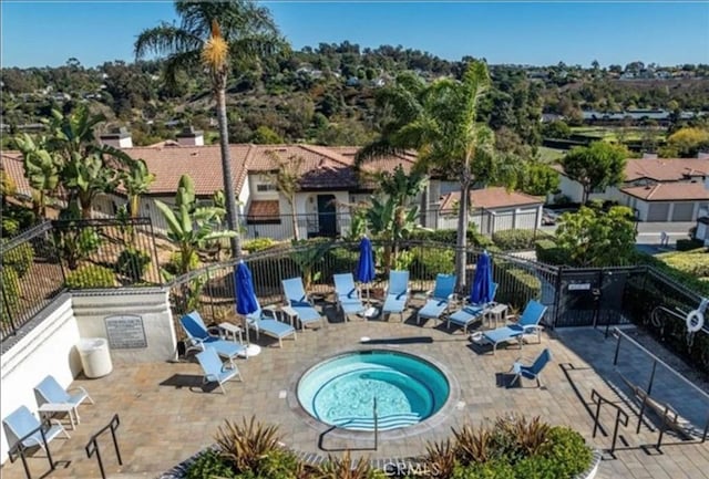 view of pool with fence, a community hot tub, and a patio area