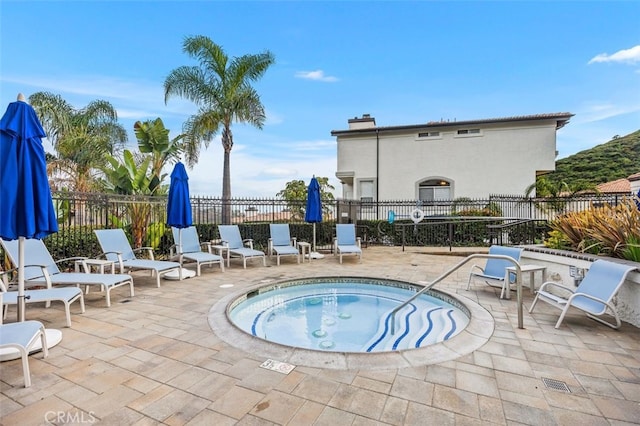 view of swimming pool with a patio, fence, and a community hot tub