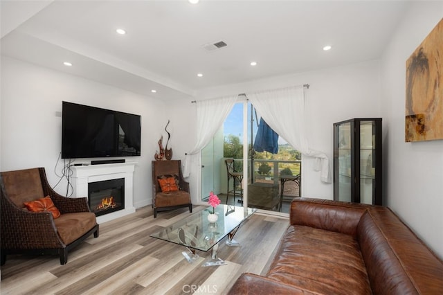 living area with recessed lighting, visible vents, and wood finished floors
