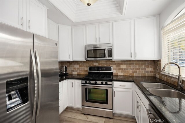 kitchen featuring a sink, decorative backsplash, white cabinets, and stainless steel appliances