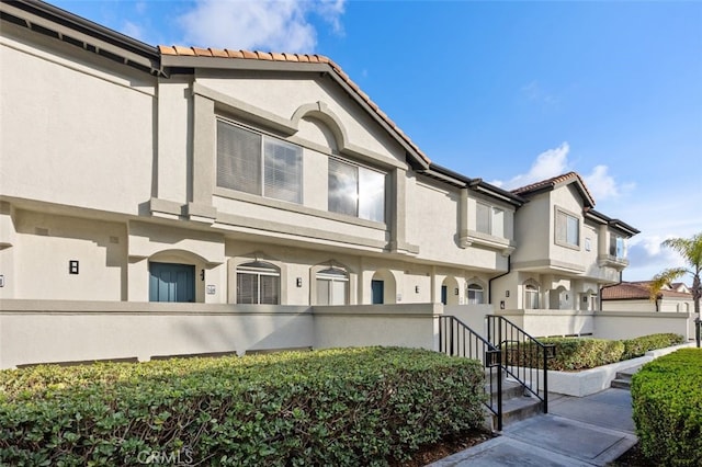 exterior space featuring stucco siding, fence, and a tile roof