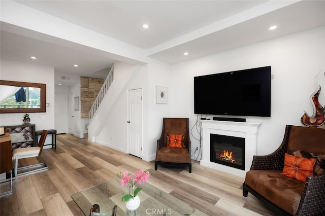 living room with light wood-style floors, recessed lighting, a glass covered fireplace, and stairs