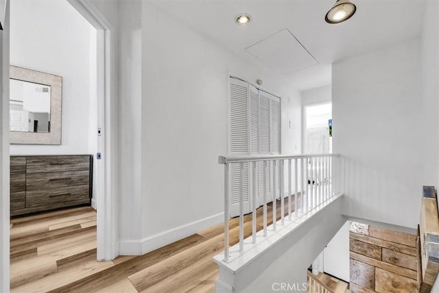 hallway with wood finished floors, baseboards, attic access, recessed lighting, and an upstairs landing