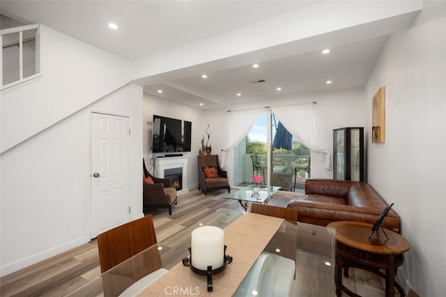 living room with visible vents, light wood-style floors, recessed lighting, baseboards, and a lit fireplace