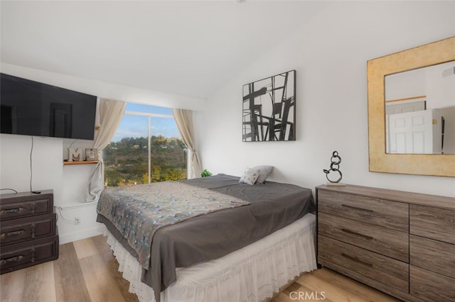 bedroom with visible vents, wood finished floors, and vaulted ceiling