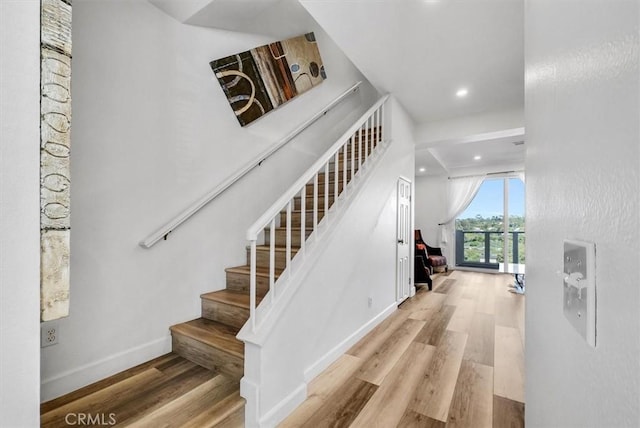 staircase with baseboards, recessed lighting, and wood finished floors