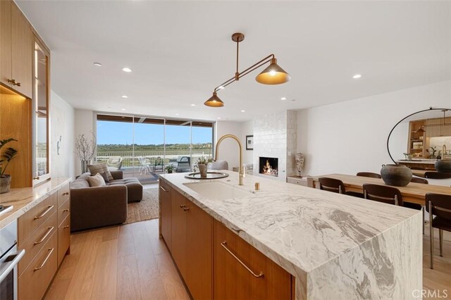 207 Canal St, Newport Beach, CA 92663 - kitchen with open floor plan, light wood-style floors, a fireplace, expansive windows, and recessed lighting