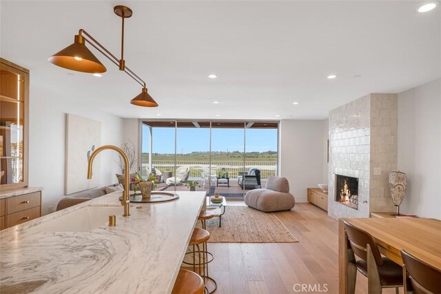 207 Canal St, Newport Beach, CA 92663 - kitchen featuring open floor plan, light wood finished floors, a large fireplace, recessed lighting, and a kitchen bar