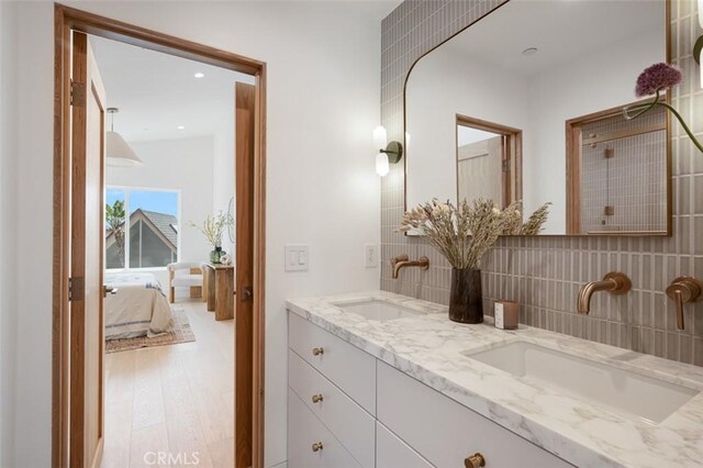 207 Canal St, Newport Beach, CA 92663 - ensuite bathroom featuring double vanity, wood finished floors, decorative backsplash, and recessed lighting