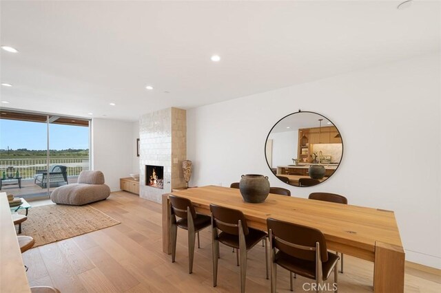 207 Canal St, Newport Beach, CA 92663 - dining area with light wood finished floors, a multi sided fireplace, recessed lighting, and floor to ceiling windows