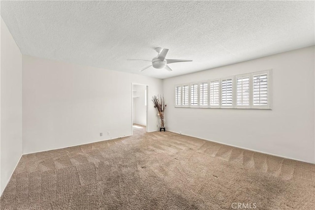 carpeted spare room with a ceiling fan and a textured ceiling