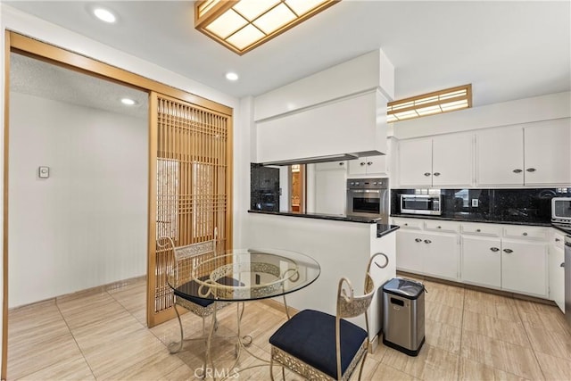 kitchen featuring dark countertops, appliances with stainless steel finishes, tasteful backsplash, recessed lighting, and white cabinetry