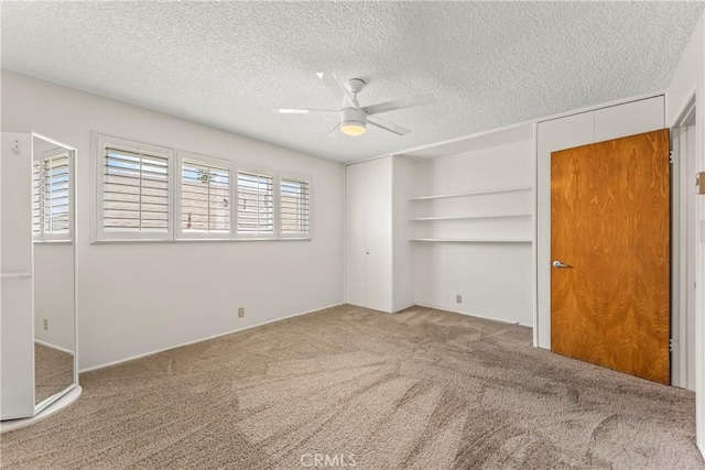 unfurnished bedroom featuring a ceiling fan, a textured ceiling, and carpet