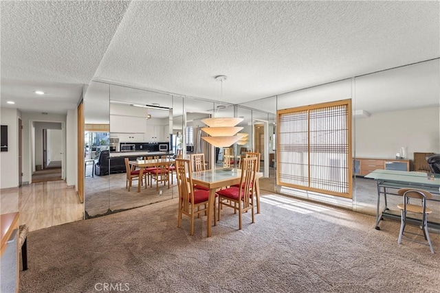 dining space featuring light carpet and a textured ceiling