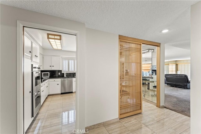 kitchen featuring white cabinets, stainless steel appliances, dark countertops, and light tile patterned floors