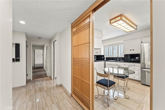 kitchen featuring white cabinets, dark countertops, stainless steel fridge, recessed lighting, and tasteful backsplash