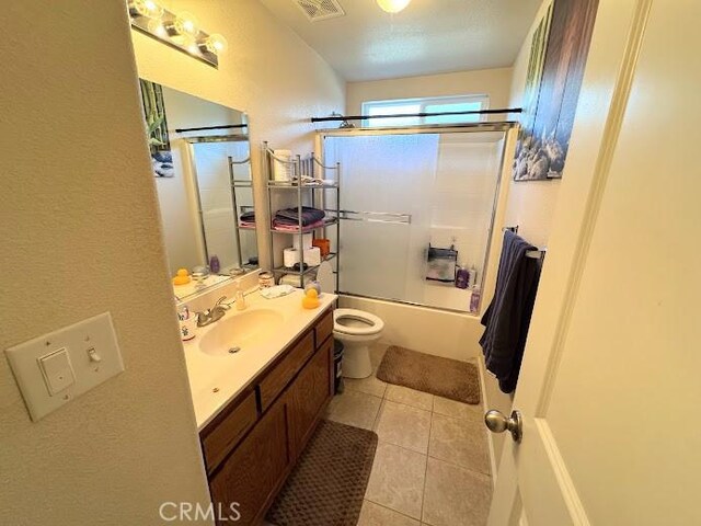 full bathroom with visible vents, tile patterned flooring, vanity, combined bath / shower with glass door, and toilet