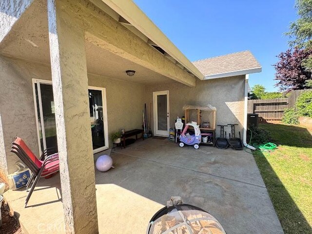 rear view of house featuring fence, stucco siding, and a patio area
