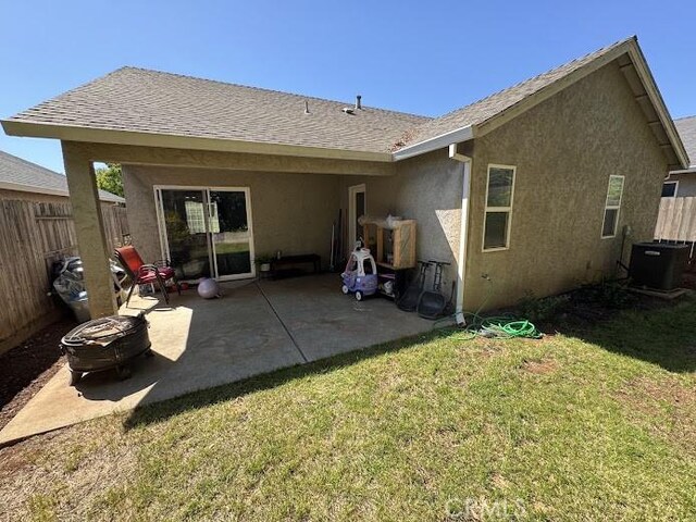 back of house featuring central air condition unit, a yard, fence, and stucco siding