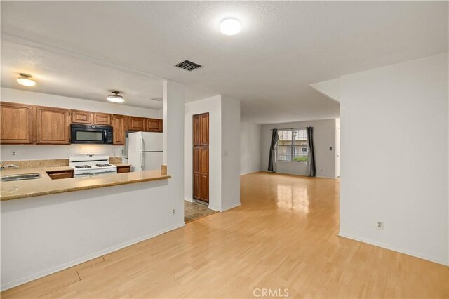 kitchen with white appliances, visible vents, a sink, and light wood finished floors