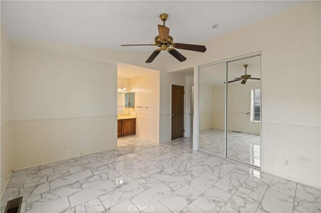 unfurnished bedroom featuring a closet, visible vents, marble finish floor, wainscoting, and ceiling fan