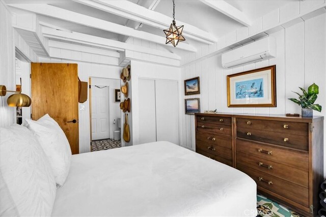 bedroom featuring a closet, a wall mounted air conditioner, and beamed ceiling