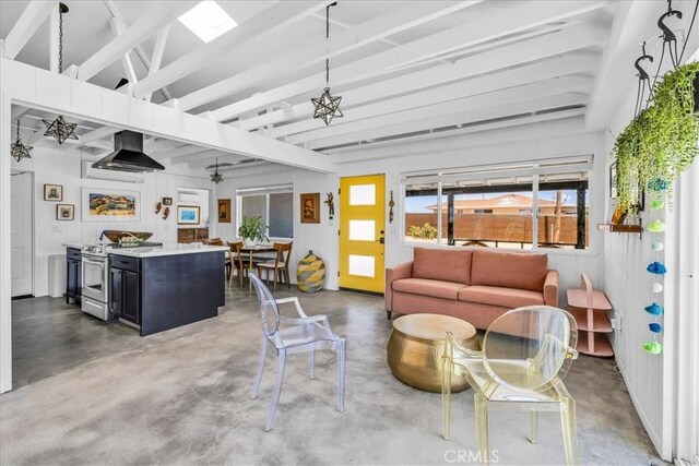 living area with a ceiling fan, finished concrete flooring, and beamed ceiling