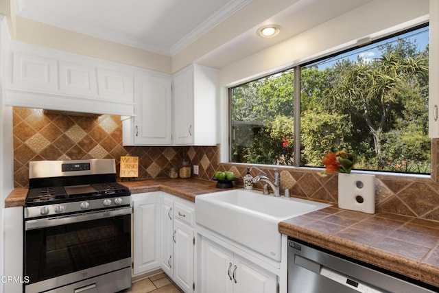 kitchen featuring tile counters, a sink, white cabinetry, and stainless steel appliances