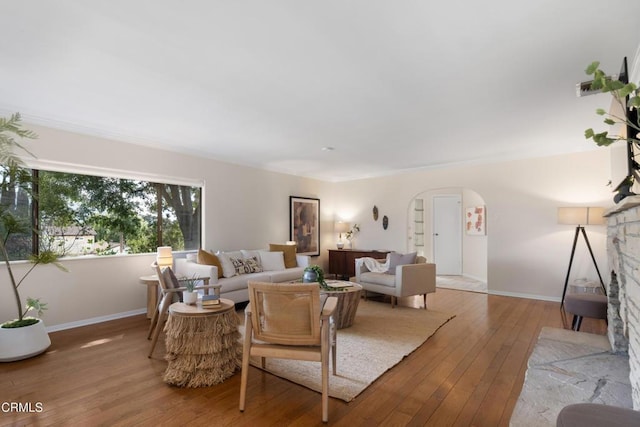 living area with arched walkways, baseboards, and hardwood / wood-style floors