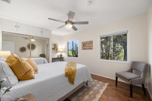 bedroom featuring ceiling fan, visible vents, dark wood finished floors, baseboards, and a closet