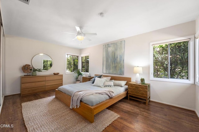 bedroom featuring baseboards, multiple windows, a ceiling fan, and wood finished floors