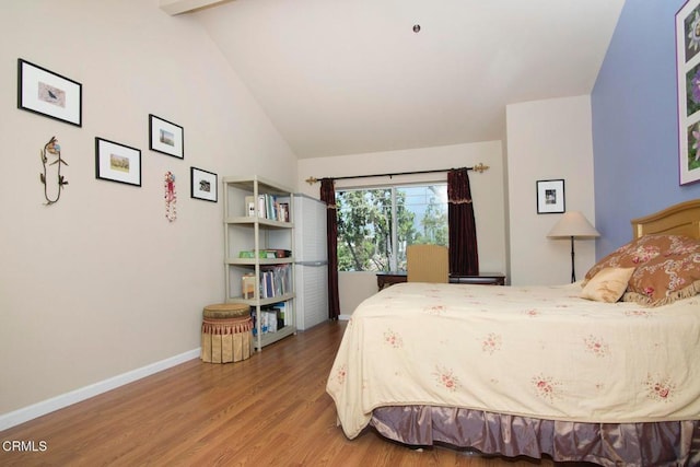bedroom with baseboards, wood finished floors, and lofted ceiling