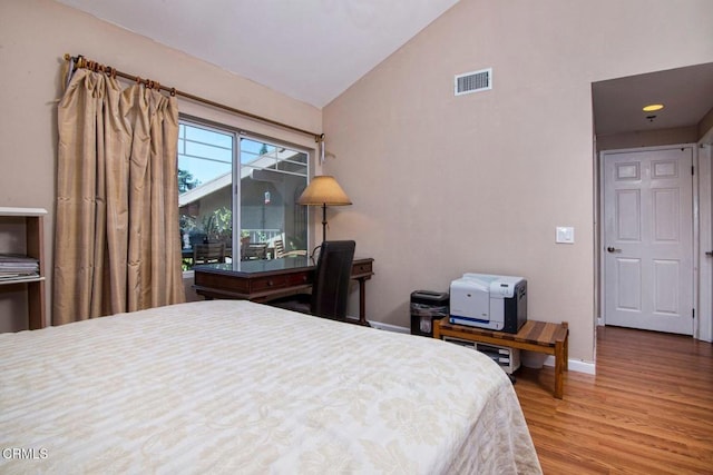 bedroom featuring visible vents, baseboards, wood finished floors, and high vaulted ceiling