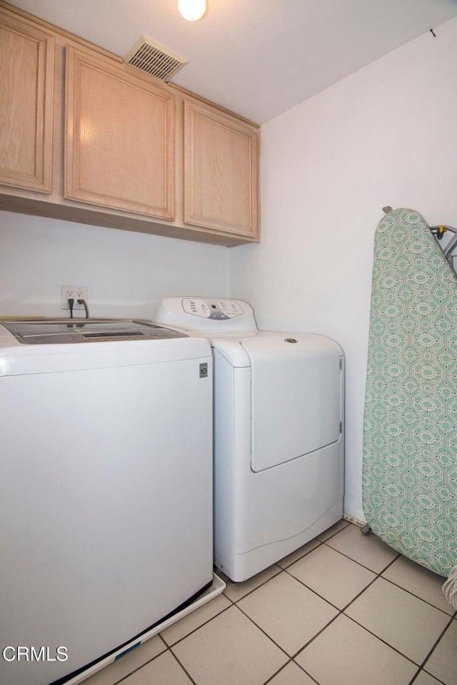 clothes washing area featuring cabinet space, visible vents, washing machine and dryer, and light tile patterned floors