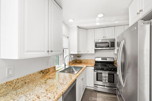kitchen with light stone countertops, recessed lighting, white cabinets, a sink, and stainless steel appliances