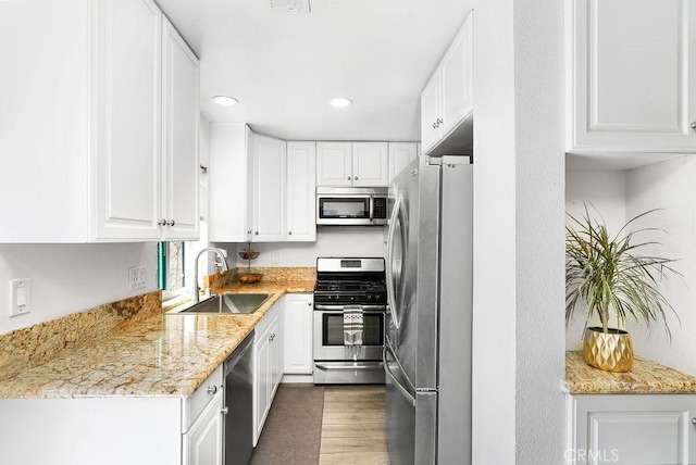kitchen with a sink, wood finished floors, white cabinets, and stainless steel appliances
