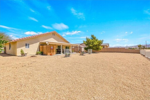 rear view of property with a tile roof, a fenced backyard, and stucco siding