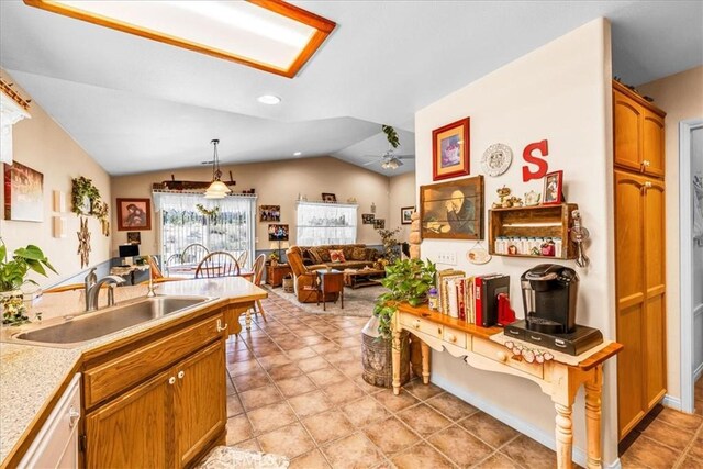kitchen featuring ceiling fan, white dishwasher, vaulted ceiling, a sink, and light countertops