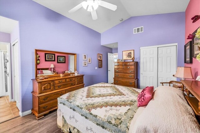 bedroom featuring high vaulted ceiling, a ceiling fan, wood finished floors, visible vents, and a closet