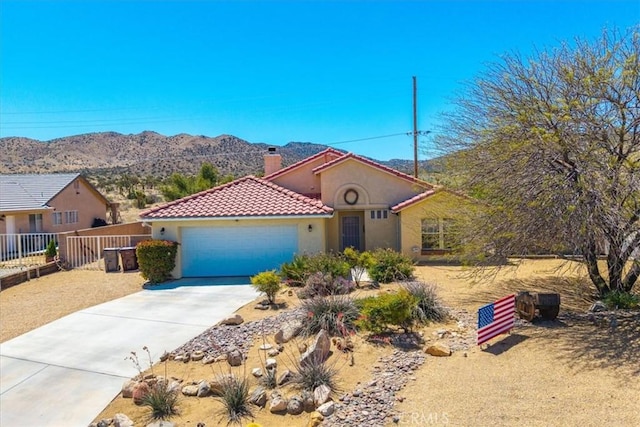 mediterranean / spanish home with a tiled roof, a chimney, concrete driveway, an attached garage, and stucco siding