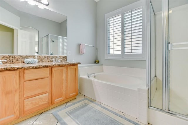 bathroom with a sink, tile patterned flooring, double vanity, a garden tub, and a stall shower