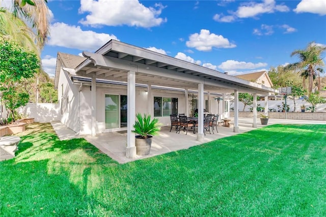 rear view of house featuring a patio, stucco siding, a yard, and fence