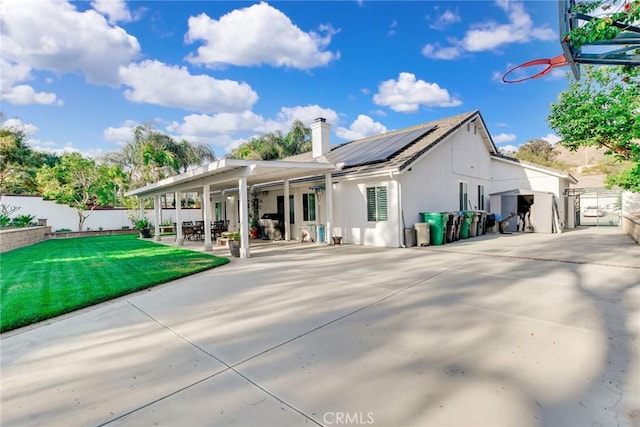 rear view of property with fence private yard, a yard, solar panels, and a patio