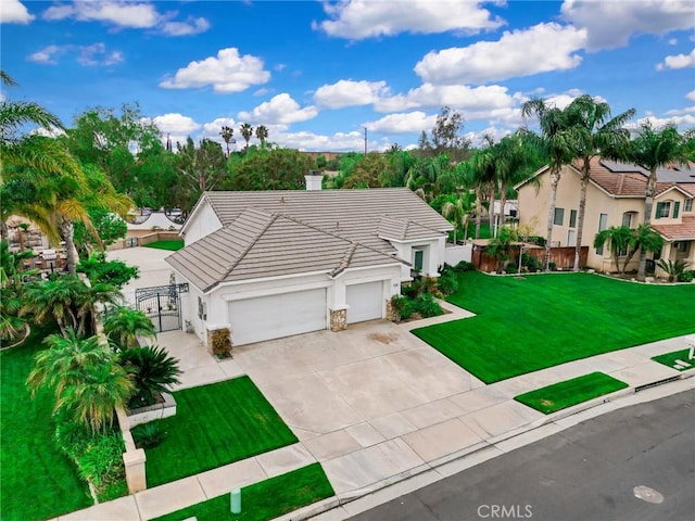 view of front of home featuring an attached garage, a front lawn, stucco siding, a gate, and a tiled roof