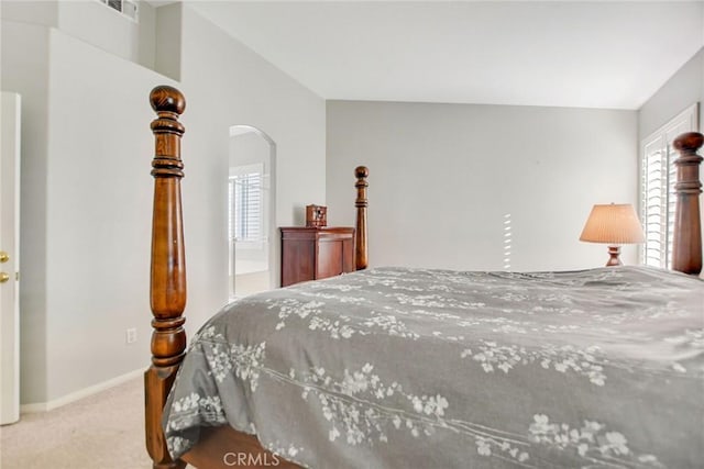 bedroom featuring arched walkways, multiple windows, carpet, and visible vents