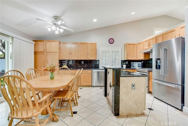 kitchen featuring light brown cabinetry, a kitchen island, stainless steel appliances, and lofted ceiling