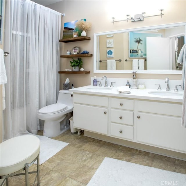 full bathroom with double vanity, toilet, curtained shower, and a sink